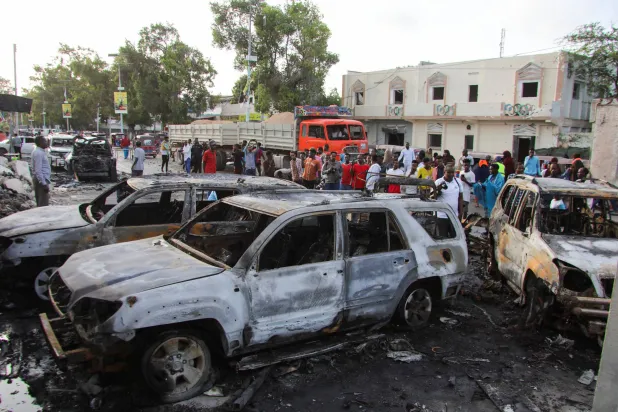 أشخاص يتجمعون بالقرب من حطام المركبات المدمرة بمكان انفجار خارج مطعم حيث كان الزبائن يشاهدون المباراة النهائية لبطولة كرة القدم الأوروبية 2024 على شاشة التلفزيون في منطقة بونديري بمقديشو الصومال في 15 يوليو 2024 (رويترز)