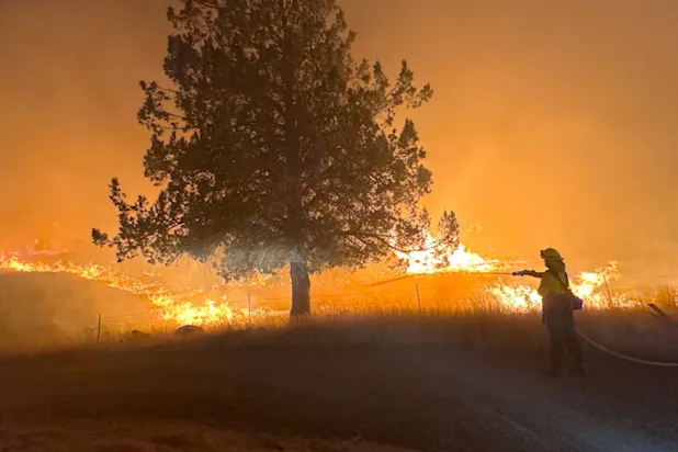 رجل إطفاء يعمل على إطفاء حريق لون روك المشتعل في سبراي بولاية أوريغون بالولايات المتحدة في 21 يوليو 2024 في لقطة الشاشة هذه التي تم الحصول عليها من مقطع فيديو (رويترز)