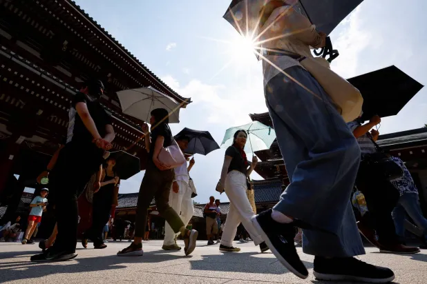 مارة يحملون مظلات يسيرون تحت أشعة الشمس القوية في معبد سينسوجي حيث أصدرت الحكومة اليابانية تنبيهات من ضربة شمس في 39 محافظة من محافظات البلاد البالغ عددها 47 محافظة... الصورة في طوكيو، اليابان 22 يوليو 2024 (رويترز)