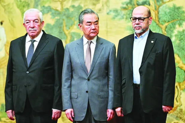 وزير الخارجية الصيني وانغ يي ونائب رئيس «فتح» محمود العالول وقيادي «حماس» موسى أبو مرزوق خلال توقيع الاتفاق في بكين أمس (أ.ب)