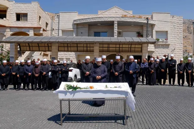 Druze elders and mourners pray by the coffin of Guevara Ibrahim, 11, killed in a reported strike from Lebanon two days earlier, during his funeral in the Druze town of Majdal Shams in the Israeli-annexed Golan on July 29, 2024. (AFP)