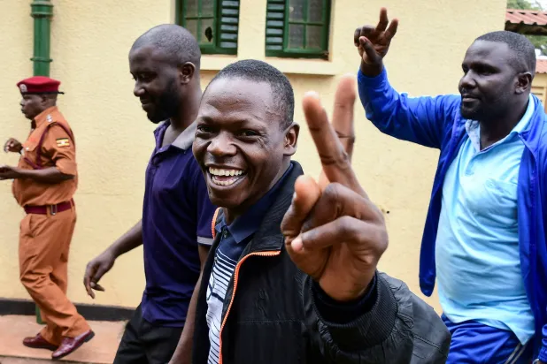 أنصار المعارضة الأوغندية يلوّحون بأيديهم بعد اتهامهم بارتكاب جرائم تتعلّق بالإرهاب بعد ترحيلهم من كينيا المجاورة بعد سفرهم لحضور دورة تدريبية بها في محكمة ناكاوا الرئيسية في كامبالا بأوغندا في 29 يوليو 2024 (رويترز)