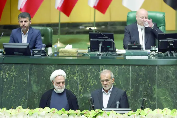 
الرئيس الإيراني مسعود بزشكيان يؤدي القسم إلى جانب رئيس القضاء غلام حسين محسني إجئي (أ.ف.ب)