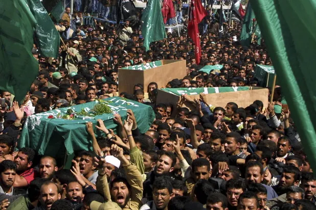 فلسطينيون يحملون نعش الشيخ أحمد ياسين (على اليسار) خلال جنازته بمدينة غزة في 22 مارس 2004 (أ.ب)