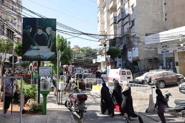 سكان من الضاحية الجنوبية لبيروت يعبرون شارعاً في حارة حريك على مقربة من موقع استهداف القيادي بـ«حزب الله» فؤاد شكر (أ.ف.ب)