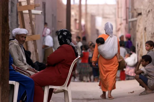 امرأة مغربية تحمل طفلاً صغيراً في أحد شوارع مراكش (أرشيفية - رويترز)
