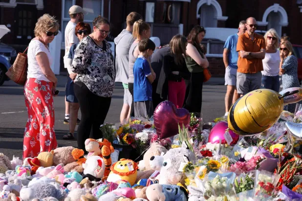 الناس ينظرون إلى تحيات الأزهار والدببة المحشوة عند تقاطع طريق تيثبارن وشارع هارت تخليداً لذكرى إلسي دوت ستانكومب وبيبي كينغ وأليس داسيلفا أغيار وهم 3 أطفال ضحايا خلال حادث طعن في ساوثبورت - بريطانيا (رويترز)