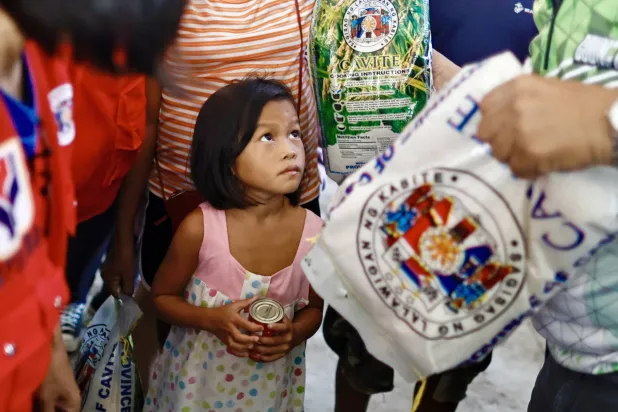 فتاة صغيرة تتلقّى مساعدات غذائية ضمن جهود إغاثية في الفلبين (إ.ب.أ)