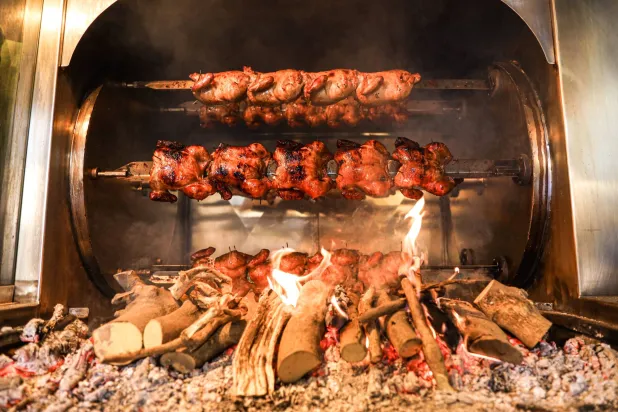 يتم تسوية الدجاج بتتبيلة برتغالية على حطب أشجار البرتقال في نيكوس (الشرق الأوسط)