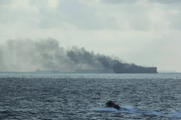 قارب مطاطي تابع للسفينة «آر إس إس سوبريم» بالقرب من السفينة المشتعلة بعد اندلاع حريق في ناقلتي نفط شمال شرق جزيرة بيدرا برانكا السنغافورية (رويترز)