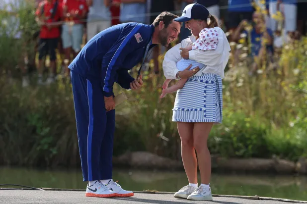 الأميركي سكوتي شيفلر يحتفل بالميدالية الذهبية في الغولف برفقة زوجته وطفله (أ.ف.ب)