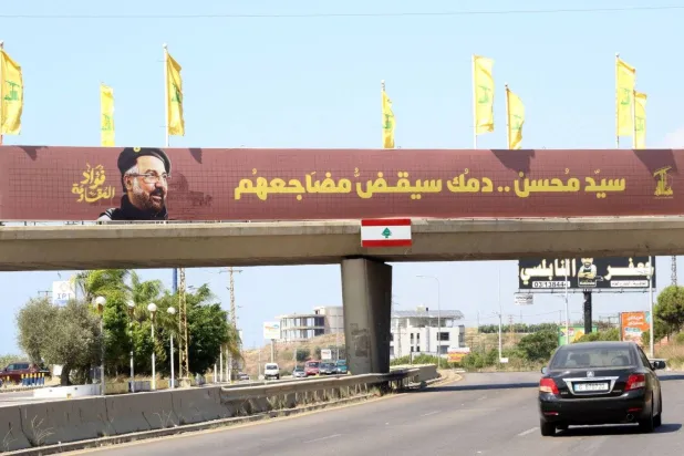 A large banner shows slain Hezbollah commander Fuad Shukr and a vow to avenge his killing. (AFP) 