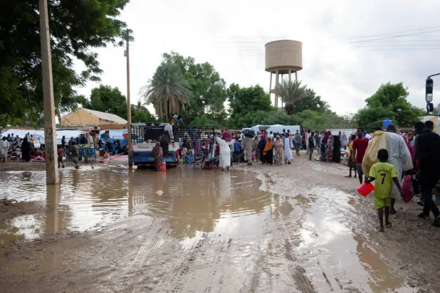 نازحون سودانيون يسيرون في شارع موحل بعد هطول أمطار غزيرة في كسلا 26 يوليو 2024 (رويترز)