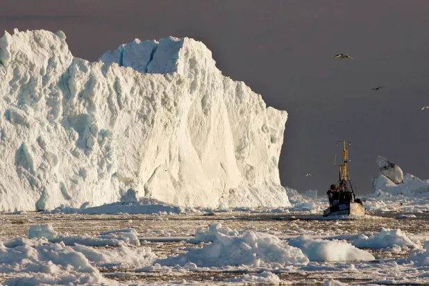 قارب صيد يبحر بجوار جبل جليدي كبير عند مصب مضيق ياكوبشافنز الجليدي بالقرب من إيلوليسات في غرينلاند في 15 مايو 2007 (رويترز)