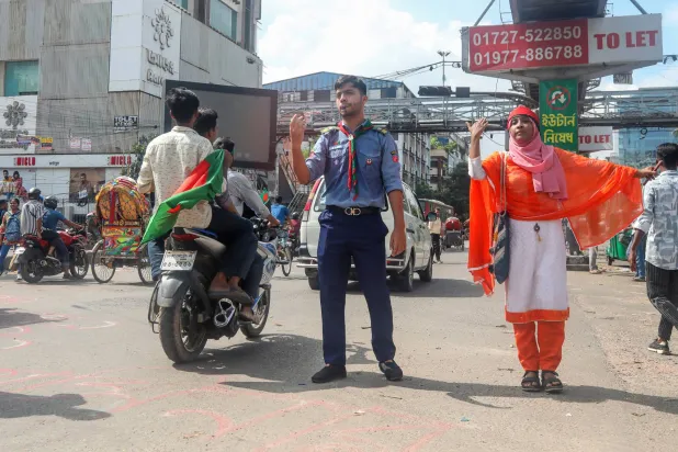 طلاب ينظمون حركة المرور في أحد شوارع دكا الثلاثاء (إ.ب.أ)