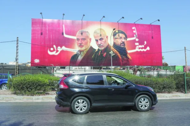 A billboard in a Beirut street features images of Ismail Haniyeh, the head of Hamas’s political bureau, Hezbollah leader Fouad Shukr, and Qasem Soleimani, commander of the Quds Force (Reuters)