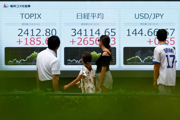 مارة ينظرون إلى لوحة إلكترونية تعرض مؤشر «توبكس» ومتوسطات أسهم «نيكي» اليابانية (رويترز)