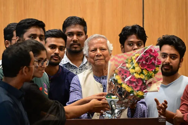 محمد يونس يحمل باقة ورد لدى وصوله إلى مطار دكا الخميس (أ.ف.ب)