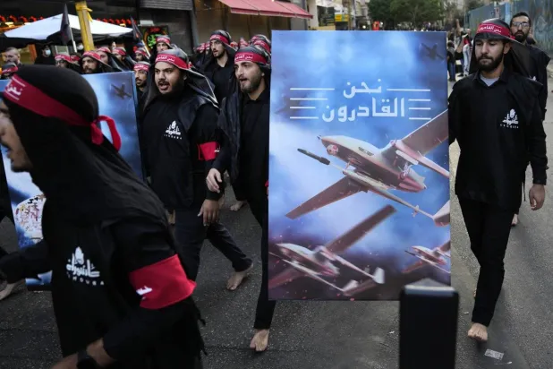 Hezbollah supporters hold up a poster of drones with the slogan “We Are Capable” during last month's Ashura commemoration (AP)