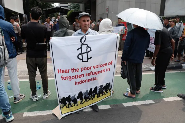 لاجئ أفغاني يحمل لافتة خلال احتجاج أمام مكتب الأمم المتحدة في جاكرتا بإندونيسيا الاثنين (إ.ب.أ)