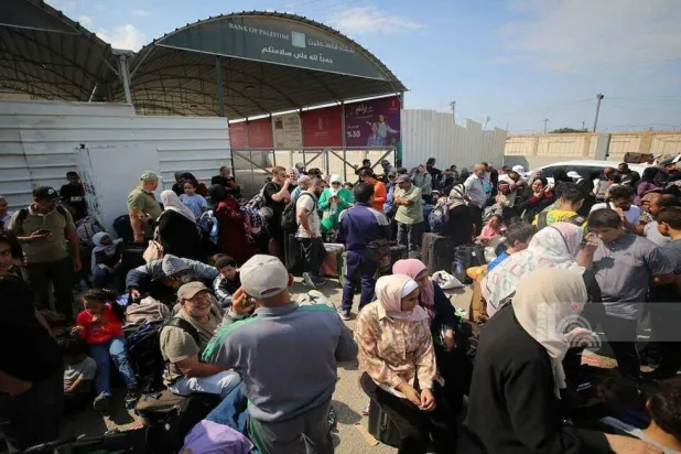 حملة جوازات أجنبية من الفلسطينيين ينتظرون على بوابة معبر رفح للحصول على إذن بالسفر بعد انطلاق حرب غزة (وفا)