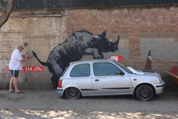 A person takes a photo of a new artwork by the British artist Banksy in Charlton, London, Britain, August 12, 2024. REUTERS/Mina Kim