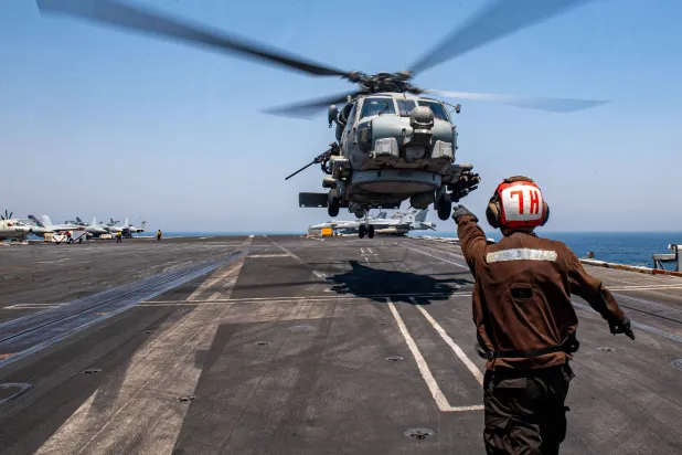 بحَّار أميركي يشير إلى مروحية من طراز «إس إتش - 60 سي هوك» خلال هبوطها على متن حاملة طائرات «يو إس إس ثيودور روزفلت» في منطقة عمليات الأسطول الخامس الأميركي 26 يوليو الماضي (البحرية الأميركية)