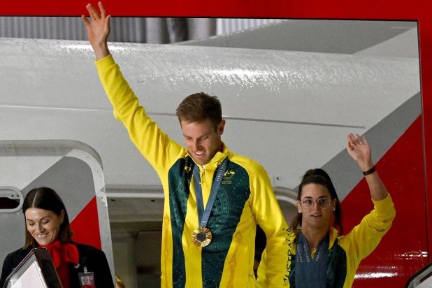 Gold medalists Australia's Matt Wearn (C) and Kaylee McKeown wave as they disembark from a chartered flight along with other athletes upon arrival at Sydney International Airport on August 14, 2024. (AFP)
