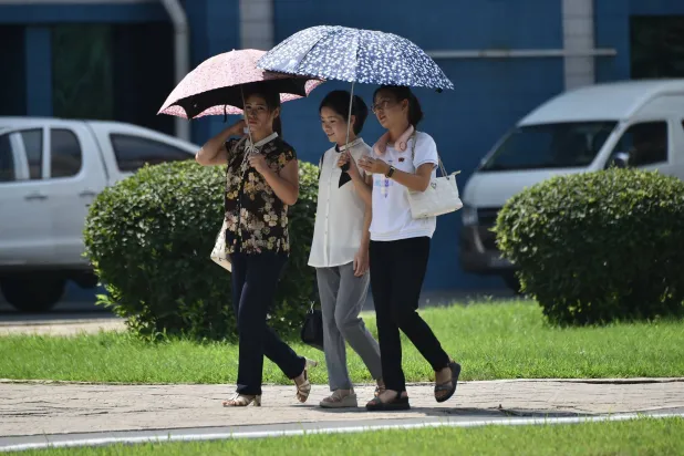 مشاة  يستخدمون المظلات لحماية أنفسهم من أشعة الشمس (أ.ف.ب)