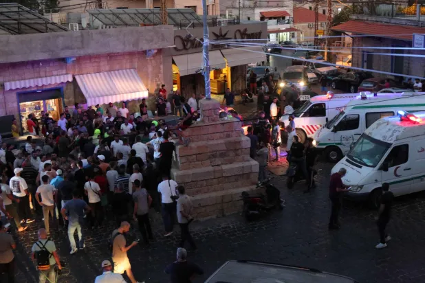 سيارات الإسعاف تصل إلى مكان الغارة الإسرائيلية بينما يتجمع الناس في أعقاب هجوم بمسيّرة إسرائيلية على الساحة الرئيسية لبلدة مرجعيون جنوب لبنان في 14 أغسطس 2024 (أ.ف.ب)