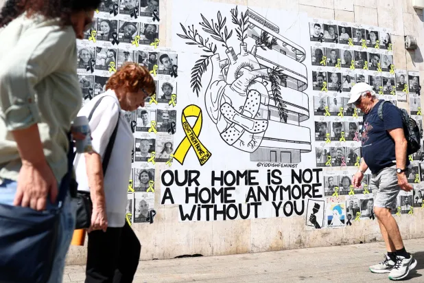 أشخاص يمشون أمام صور تذكارية لرهائن إسرائيل بيد «حماس» منذ هجوم 7 أكتوبر (رويترز)