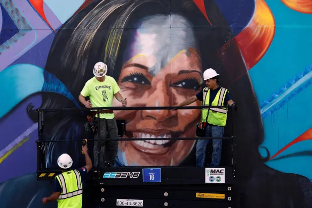 عمال يُنشئون جدارية للمرشحة الديمقراطية هاريس عشية المؤتمر الوطني الديمقراطي في شيكاغو بإلينوي (أ.ف.ب)