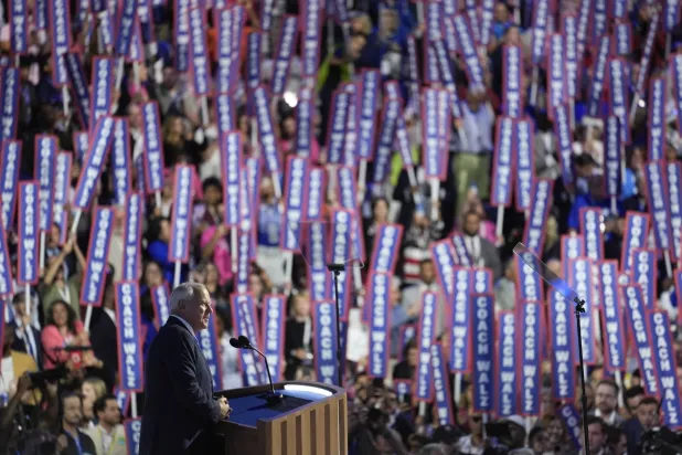 حمل المشاركون في المؤتمر لافتات «المدرب والز» خلال خطابه في 21 أغسطس (أ.ب)