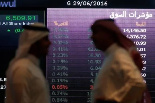 رجلان أمام شاشة التداول في السوق المالية السعودية (رويترز)