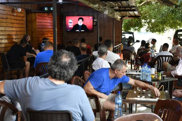 Citizens listen to Hezbollah Secretary-General Hassan Nasrallah at a café in the southern suburbs of Beirut on Sunday evening, just hours after the party’s attack on northern Israel in response to the assassination of leader Fouad Shukr (EPA)