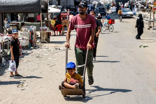 فلسطيني يدفع عربة عليها طفله في قطاع غزة (أ.ف.ب)