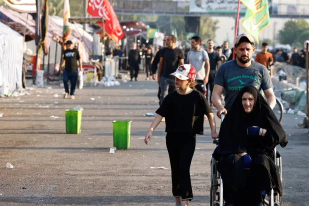 عراقيون يسيرون في أحد شوارع بغداد (رويترز)