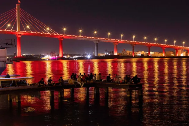 مواطنون قبالة جسر على شط العرب في البصرة جنوب العراق يوم الأحد (أ.ف.ب)