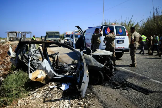 عناصر من الدفاع المدني أمام السيارة المستهدفة بالغارة الإسرائيلية على طريق الناقورة التي أدت إلى مقتل مدنيين لبنانيين اثنين (إ.ب.أ)