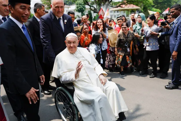 بابا الفاتيكان والرئيس الإندونيسي يحيون الجماهير قبل اجتماع مع الهيئات والمجتمع الدني والدبلوماسيين في القصر الرئاسي (أ.ف.ب)