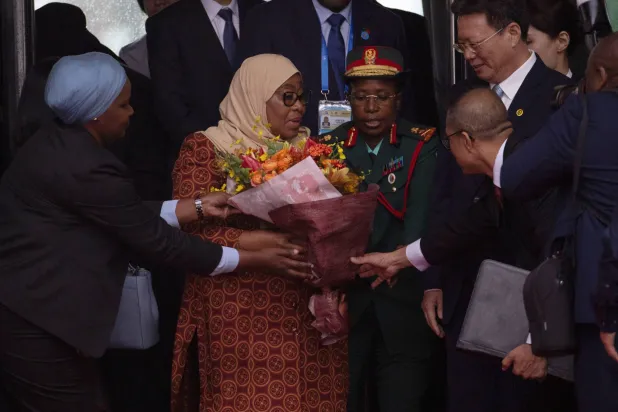 رئيسة تنزانيا سامية صولحو حسن تتلقى باقة من الورود من مسؤولين صينيين لدى وصولها إلى مطار العاصمة بكين (رويترز)