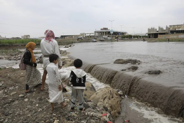 A person and his children stand near a flooded stream caused by heavy rain, in Sanaa, Yemen, 02 September 2024. EPA/YAHYA ARHAB