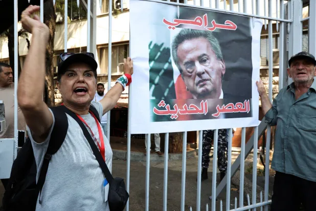 متظاهران أمام قصر العدل في بيروت يطالبان بمحاسبة سلامة (رويترز)