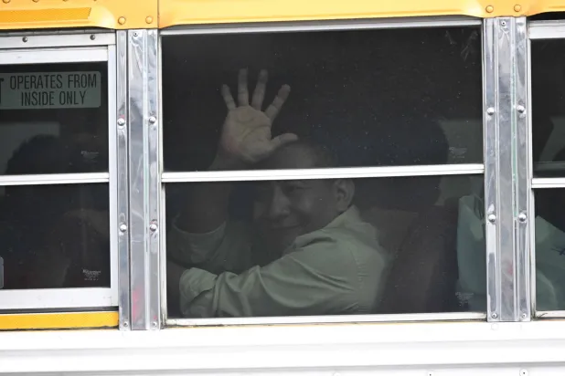 سجين سياسي نيكاراغوي يلوّح بيده على متن حافلة لدى وصوله إلى القاعدة الجوية في مدينة غواتيمالا في 5 سبتمبر 2024 (أ.ف.ب)