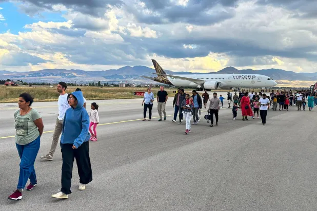 ركاب طائرة «فيستارا» من مومباي إلى فرنكفورت يسيرون على طول المدرج في مطار أرضروم بشرق تركيا (أ.ب)
