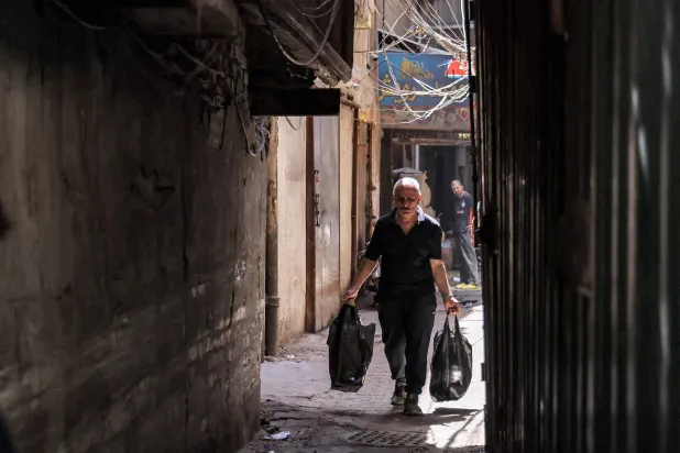 رجل عراقي يحمل حاجياته ويعبر زقاقاً في أحد أحياء بغداد القديمة (أ.ف.ب)