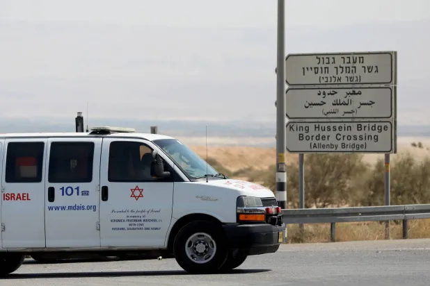 سيارة خدمات طبية تسير بالقرب من موقع إطلاق سائق شاحنة النار على جسر أللنبي المعروف أيضاً باسم جسر الملك حسين بالقرب من أريحا في الضفة الغربية (إ.ب.أ)