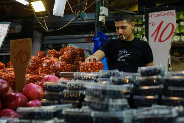 A vegetable seller arranges boxes of tomatoes at a market in Tel Aviv (Getty Images)