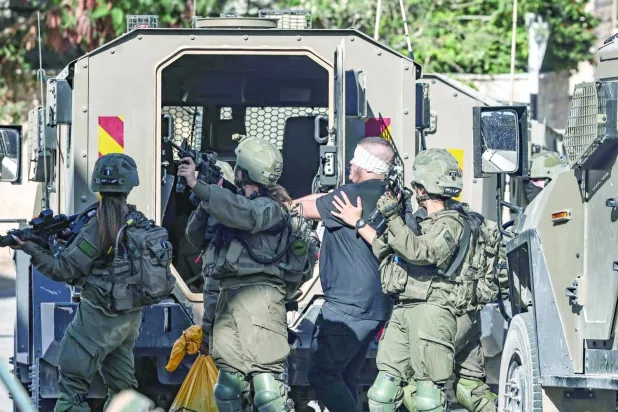 Dün Tubas'ta tutuklanan gözleri bağlı bir Filistinliyi askeri araca bindiren İsrail askerleri (AFP)