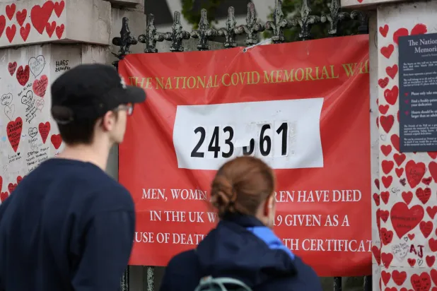 أشخاص ينظرون إلى الجدار التذكاري الوطني لـ«كوفيد» في لندن (رويترز)
